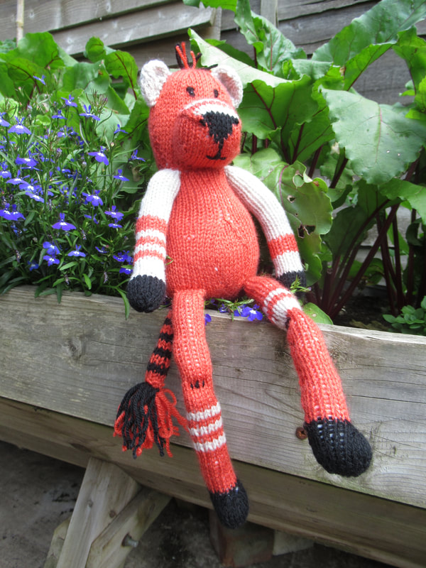Photograph of stripey bear that is hand knitted and available on Etsy to buy