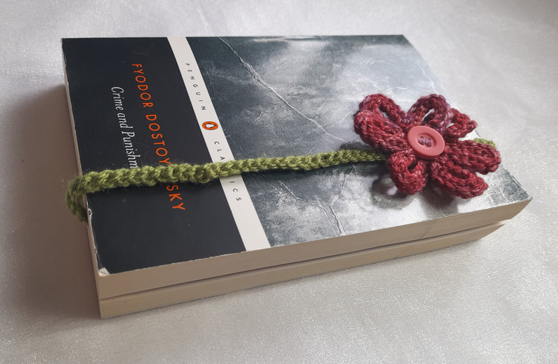 Floral book mark that has been hand knitted and attached to a crocheted cord to keep your page marked. 