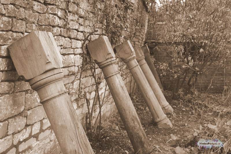 Wooden Coloumns being used to prop up an old stone wall in CAmers, South Gloucestershire, England. Photograph
