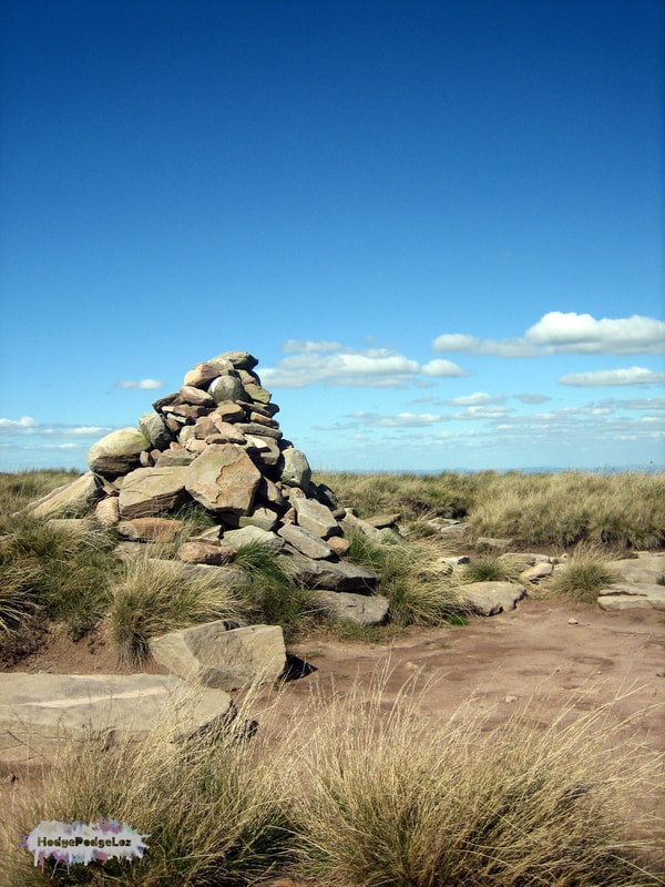 Photograph of a cairn on a Welsh hilltop. Blue sky